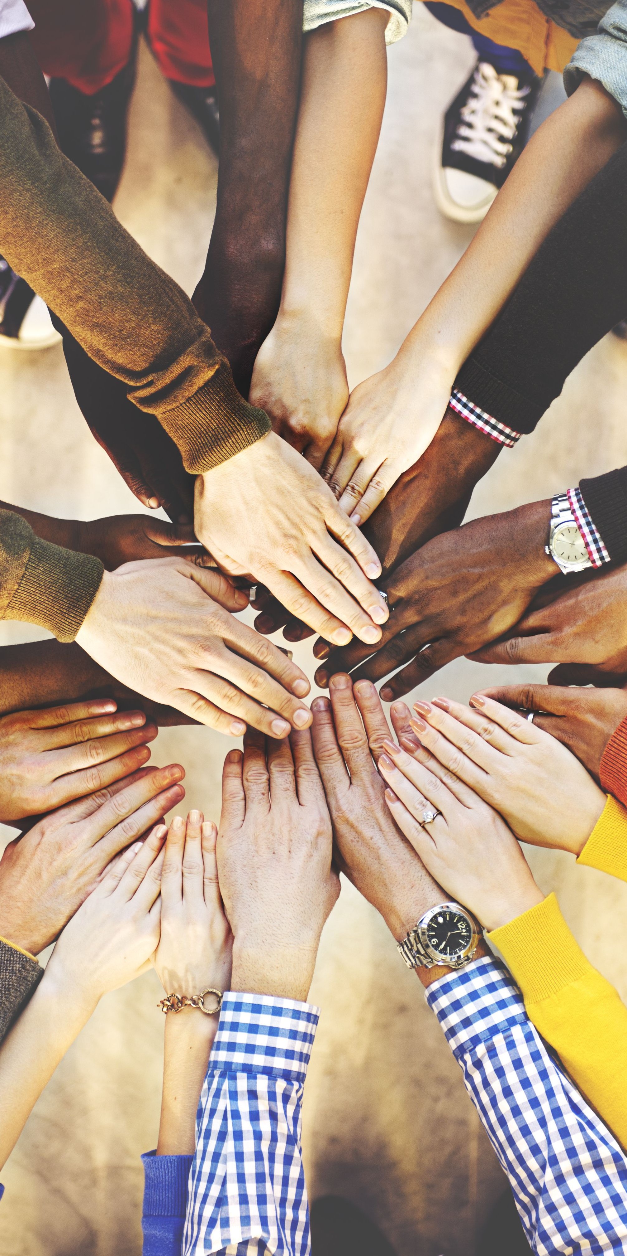 Viele Personen halten ihre Hände aufeinander (Teamwork-Konzept / Zusammengehörigkeit)