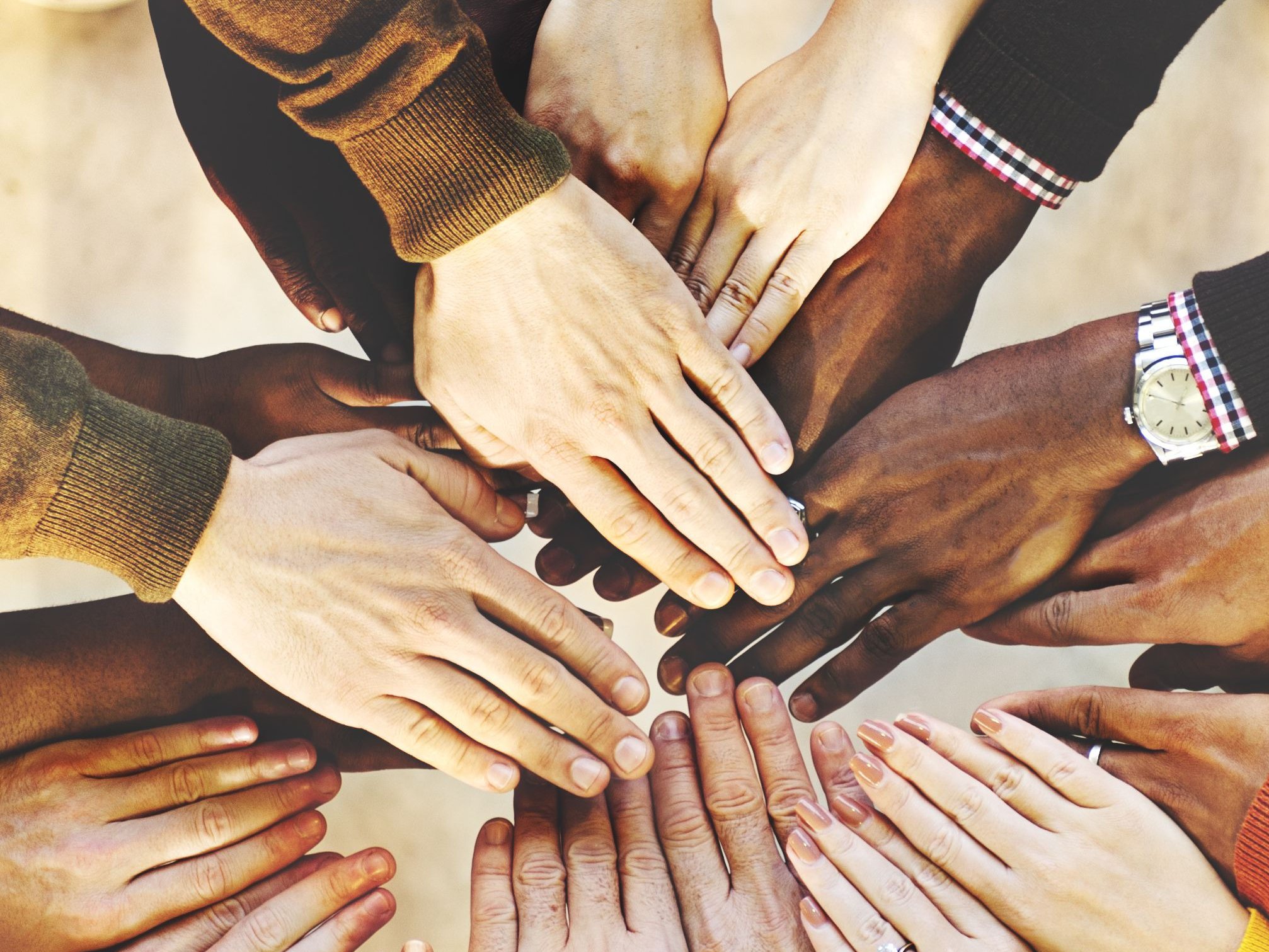 Viele Personen halten ihre Hände aufeinander (Teamwork-Konzept / Zusammengehörigkeit)