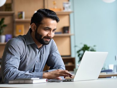 Lächelnder Mann, der zu Hause auf einem Laptop arbeitet