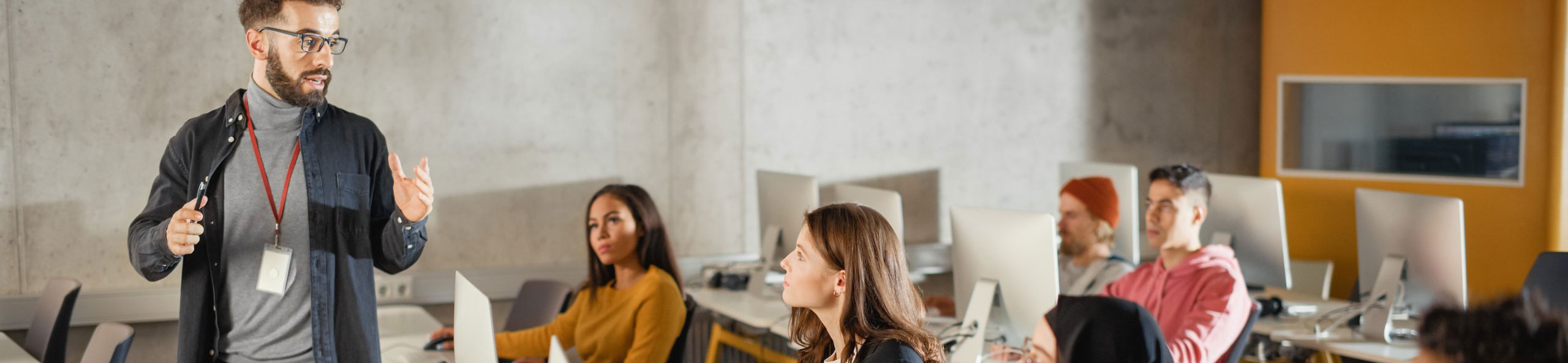 Dozent unterricht eine Gruppe Menschen, die an Computer-Arbeitsplätzen sitzen