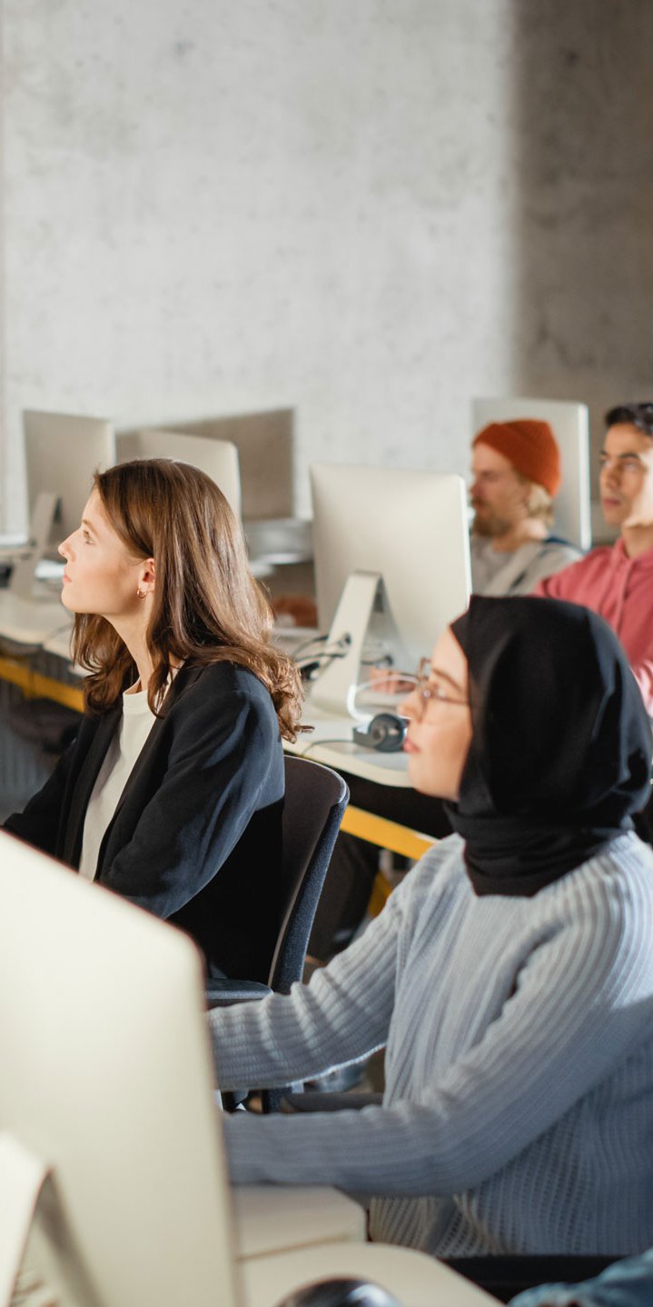 Dozent unterricht eine Gruppe Menschen, die an Computer-Arbeitsplätzen sitzen