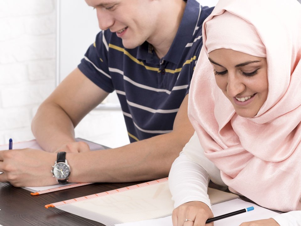 Dozentin und vier am Tisch sitzende Schüler