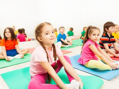 Mehrere Kinder, die auf Turnmatten sitzen