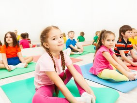 Mehrere Kinder, die auf Turnmatten sitzen