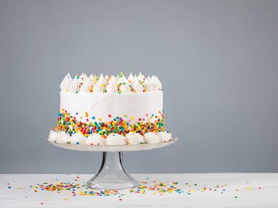 Buttercreme-Geburtstagstorte mit bunten Streuseln auf neutralem Hintergrund