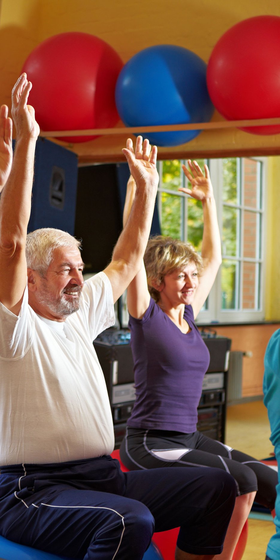 Senioren, die Rückenübungen in einem Fitnessraum machen, auf Sitzball sitzend