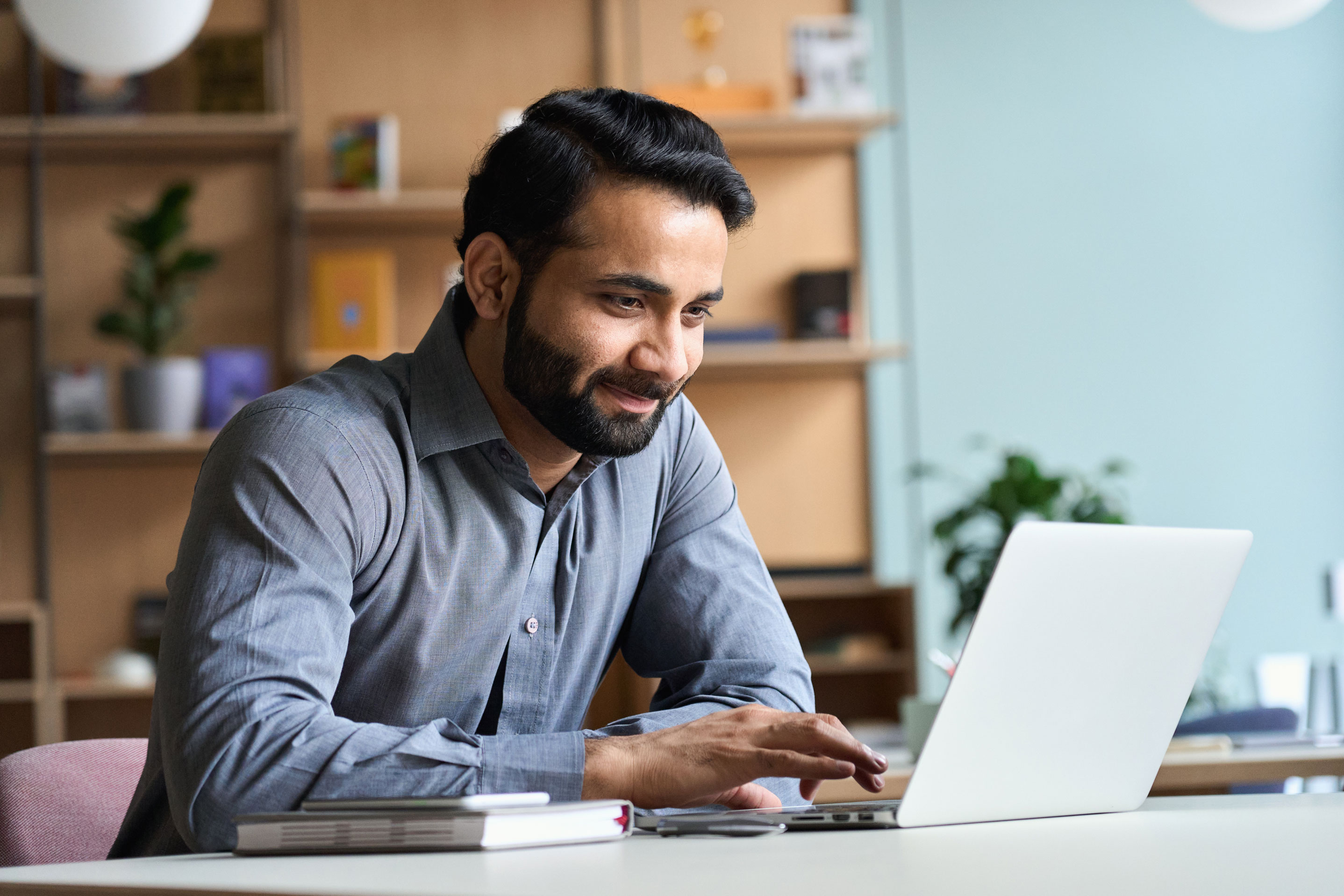 Lächelnder Mann, der zu Hause auf einem Laptop arbeitet