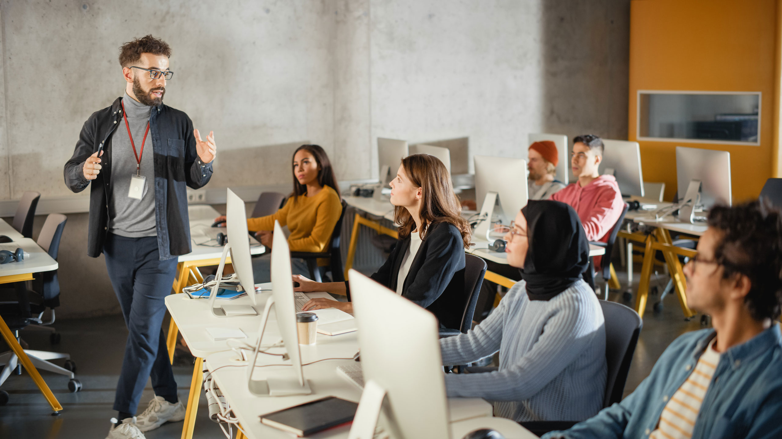 Dozent unterricht eine Gruppe Menschen, die an Computer-Arbeitsplätzen sitzen